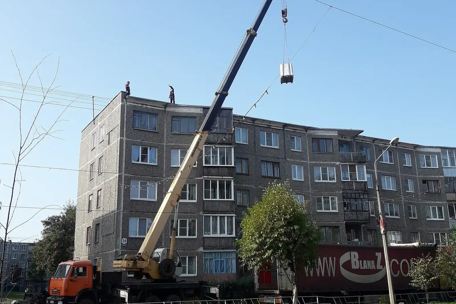 A crane lifting materials for roof repairs on an apartment block