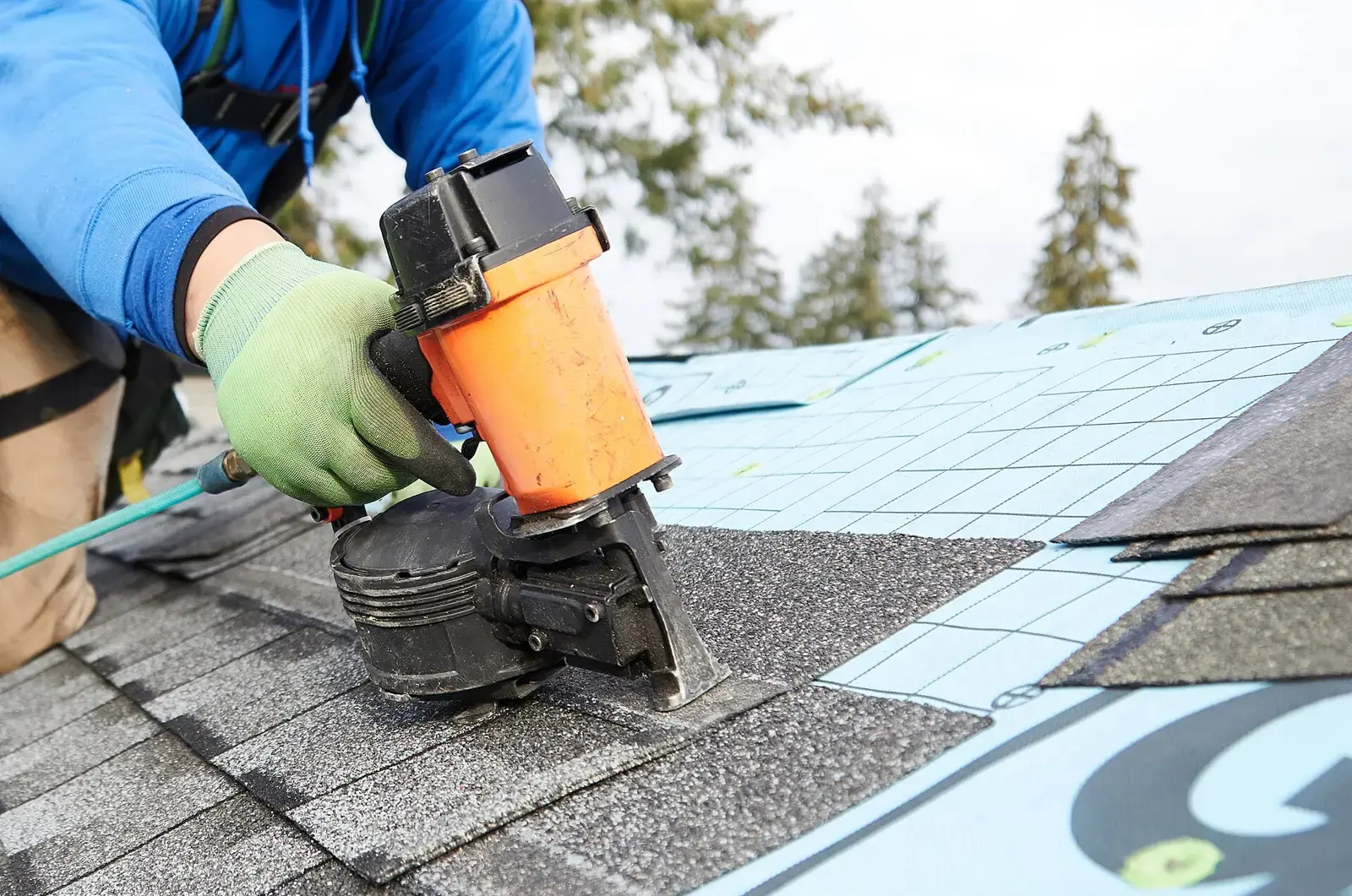 A roofer fastening shingles on a residential roof